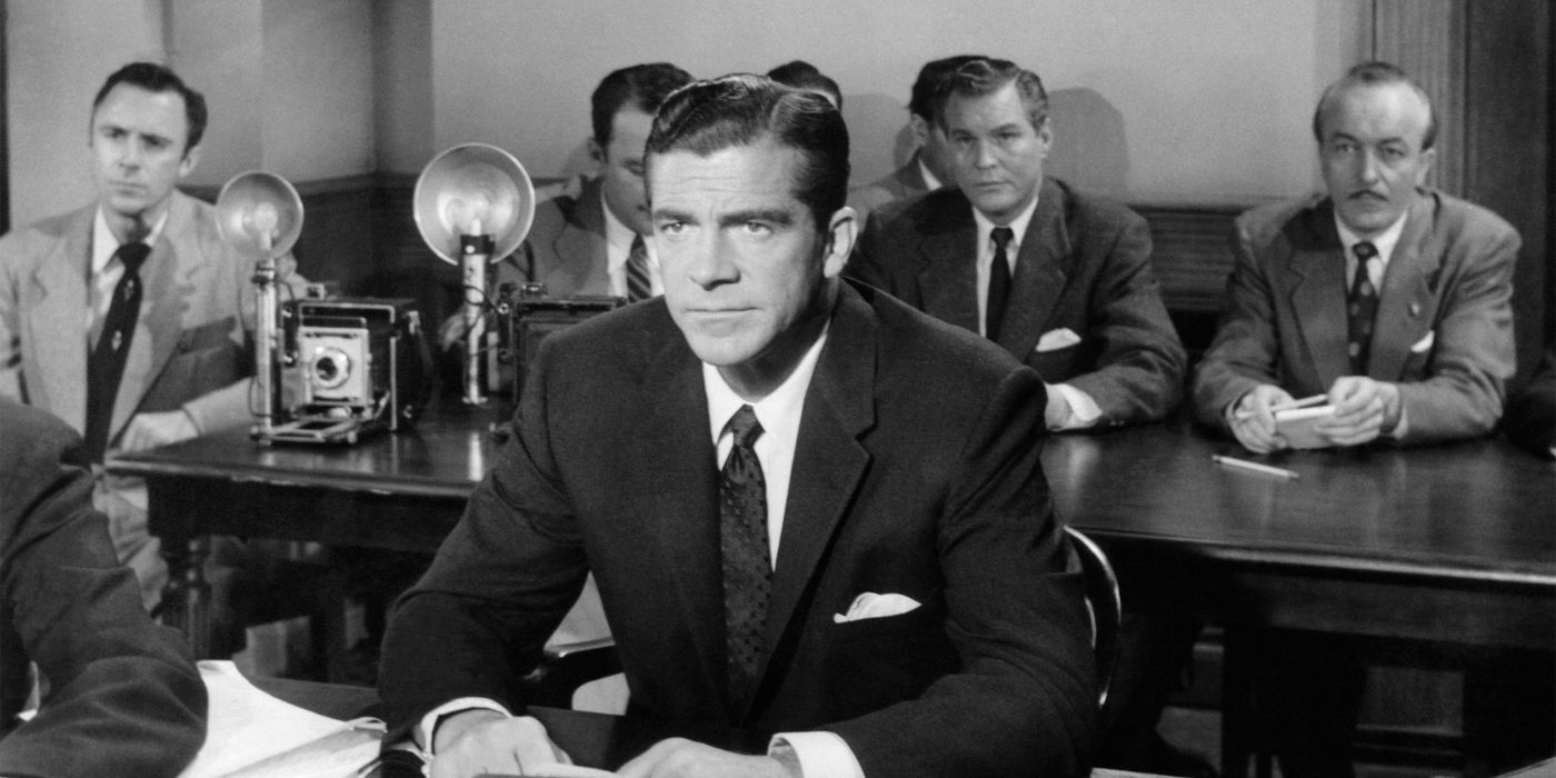 Dana Andrews assise à une table au tribunal dans Au-delà de tout doute raisonnable