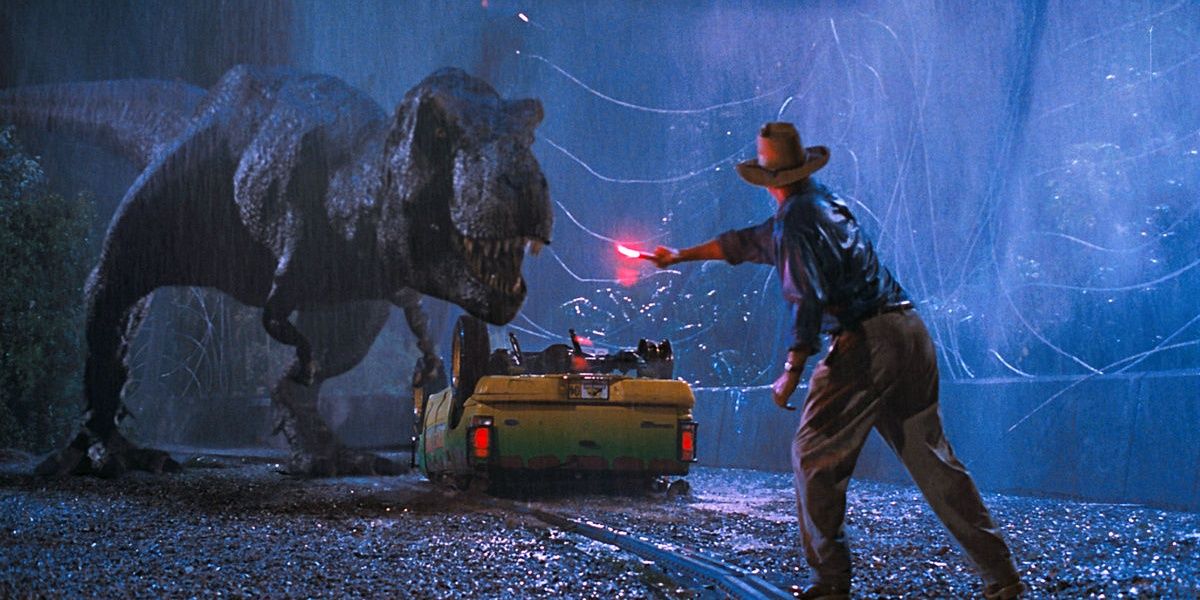 Un T-Rex debout à quelques mètres d'un homme tenant une fusée éclairante pour le distraire
