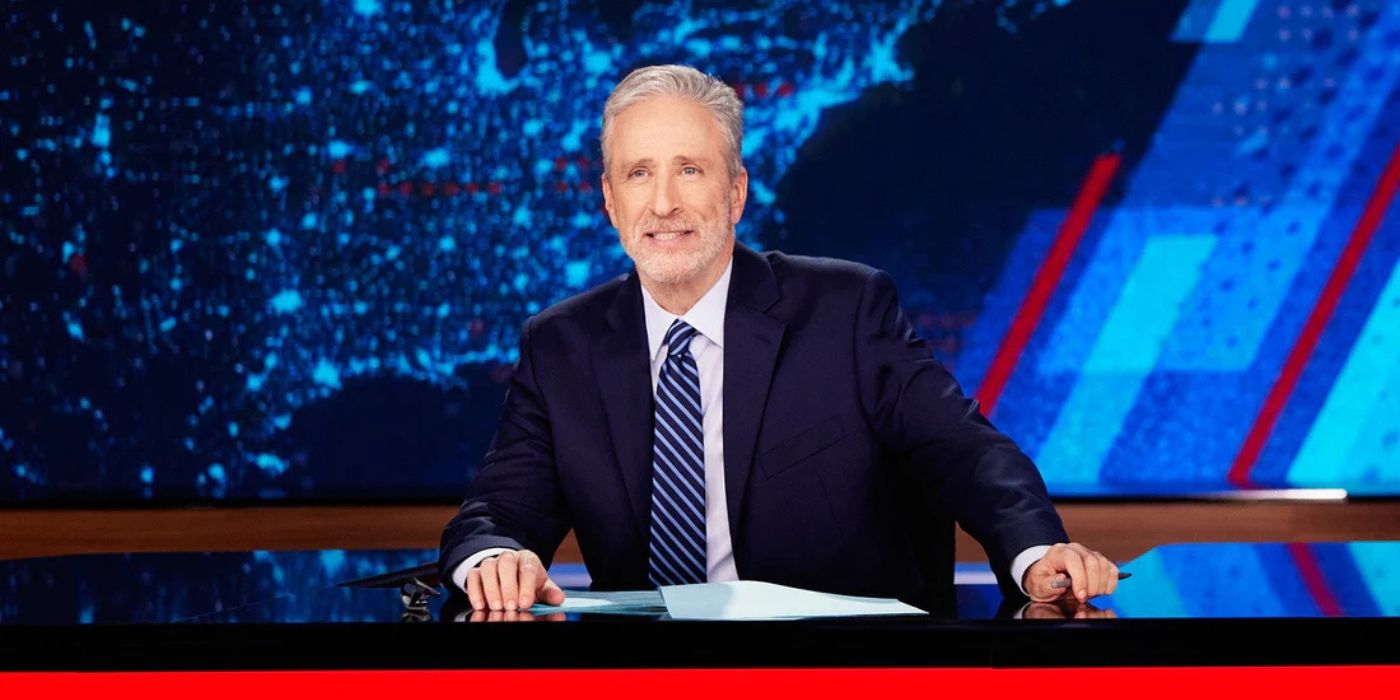 Jon Stewart sits at the desk on