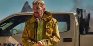 Billy Bob Thornton standing in front of a truck with a work jacket on