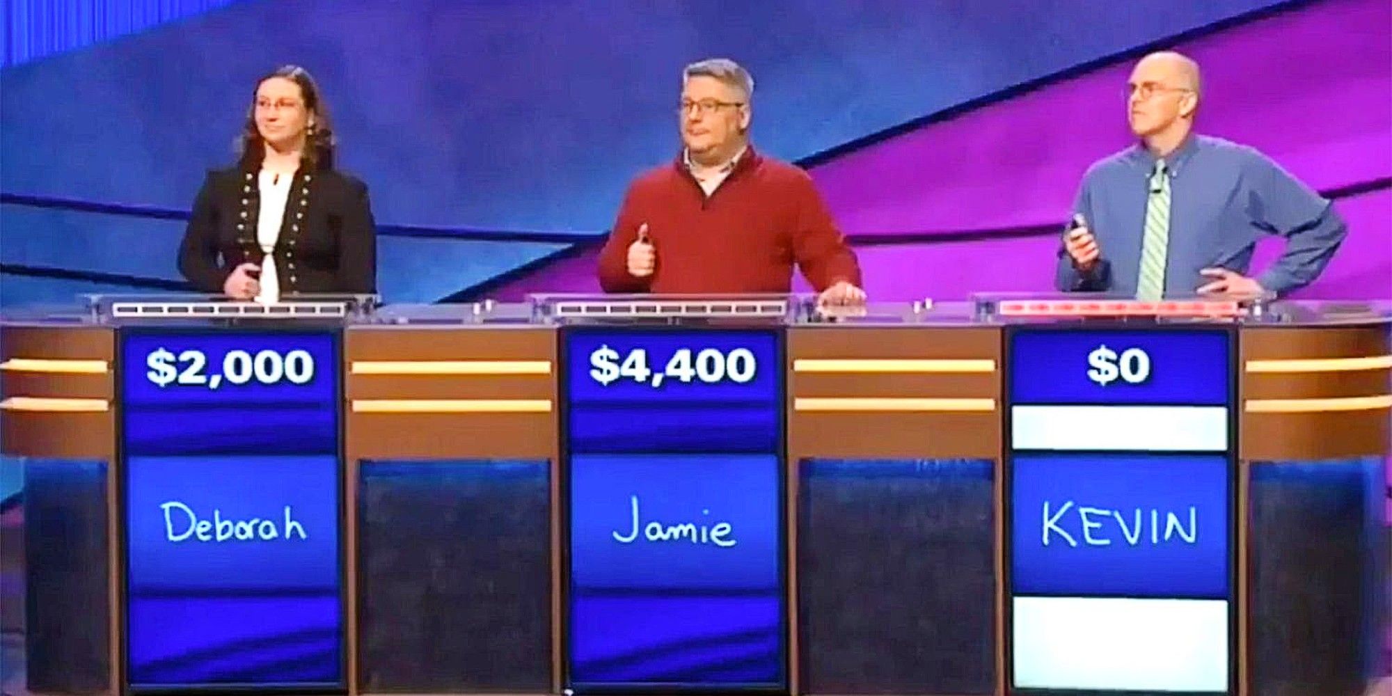 Concours Deborah, Jamie et Kevin sur les podiums avec leurs noms écrits et leurs montants en dollars sur Jeopardy.