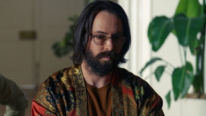 Martin Starr as Bodhi wearing a patterned shirt, tilting his head slightly down, in Tulsa King Season 1, Episode 9.